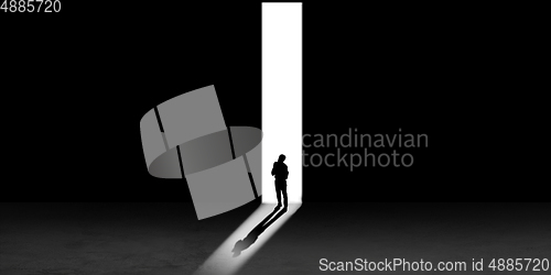 Image of Silhouette of man walking in the night toward the light, view from above