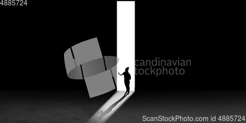 Image of Silhouette of man walking in the night toward the light, view from above