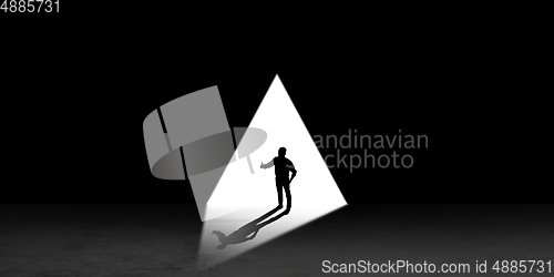 Image of Silhouette of man walking in the night toward the light, view from above