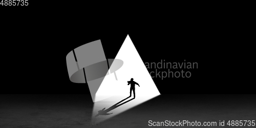 Image of Silhouette of man walking in the night toward the light, view from above