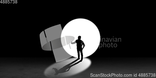 Image of Silhouette of man walking in the night toward the light, view from above