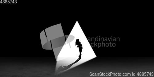 Image of Silhouette of man walking in the night toward the light, view from above