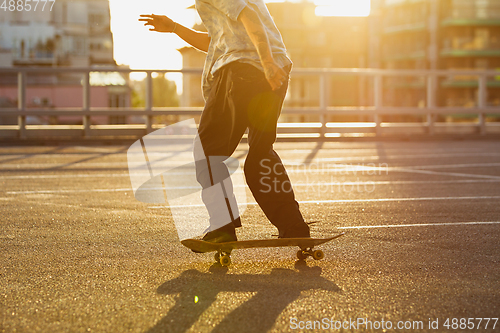 Image of Skateboarder doing a trick at the city\'s street in summer\'s sunshine