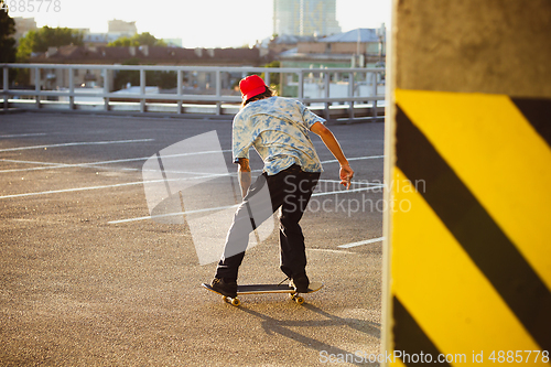 Image of Skateboarder doing a trick at the city\'s street in summer\'s sunshine