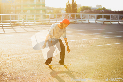 Image of Skateboarder doing a trick at the city\'s street in summer\'s sunshine