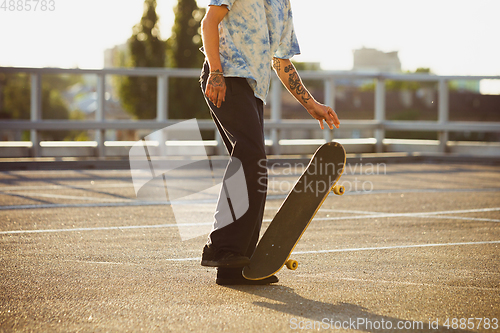 Image of Skateboarder doing a trick at the city\'s street in summer\'s sunshine