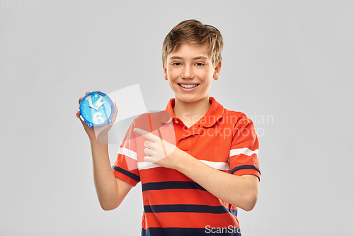 Image of portrait of happy smiling boy with alarm clock