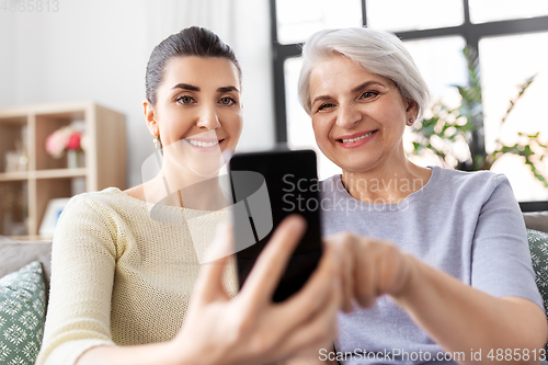 Image of daughter and senior mother with smartphone at home