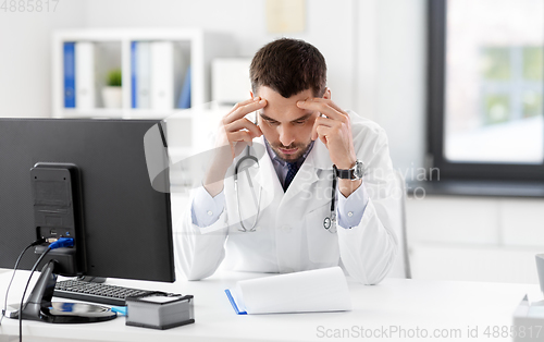 Image of stressed male doctor with clipboard at hospital