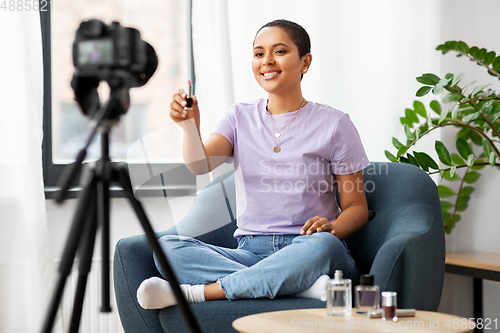 Image of female beauty blogger with camera and lipstick