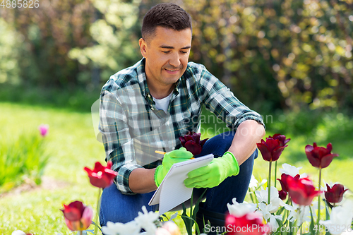 Image of man with notebook and flowers at summer garden