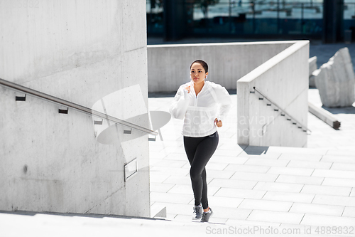 Image of african american woman running upstairs outdoors