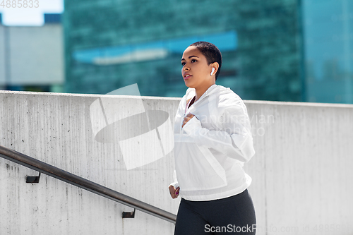 Image of african american woman running upstairs outdoors