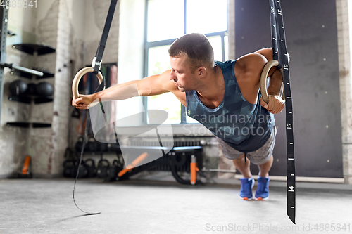 Image of man doing exercising on gymnastic rings in gym