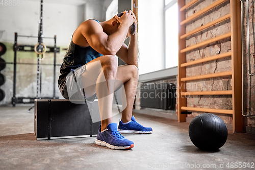 Image of tired young man with medicine ball in gym