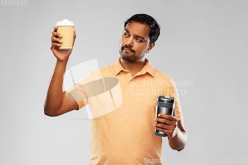 Image of man comparing thermo cup or tumbler and coffee cup