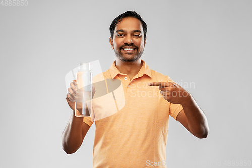 Image of happy indian man showing water in glass bottle