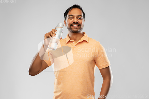 Image of happy indian man drinking water from glass bottle