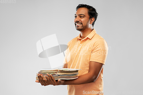 Image of smiling young indian man sorting paper waste