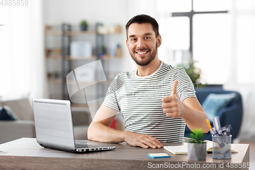 Image of happy man with laptop working at home office