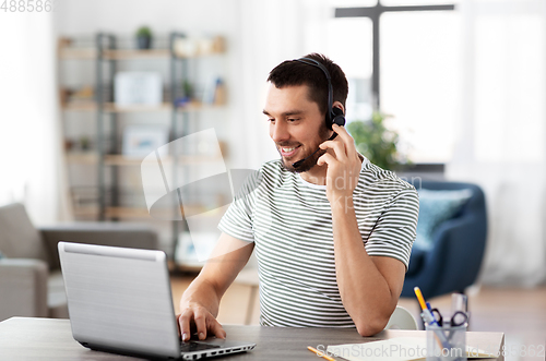 Image of man with headset and laptop working at home