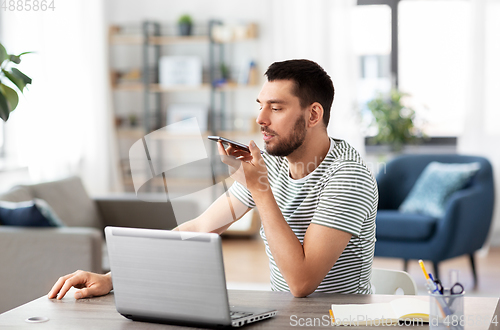 Image of man with laptop calling on phone at home office