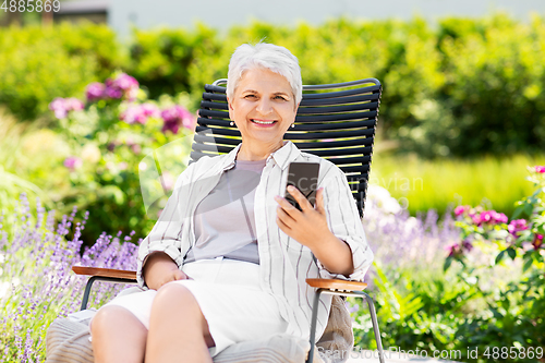 Image of happy senior woman with phone at summer garden