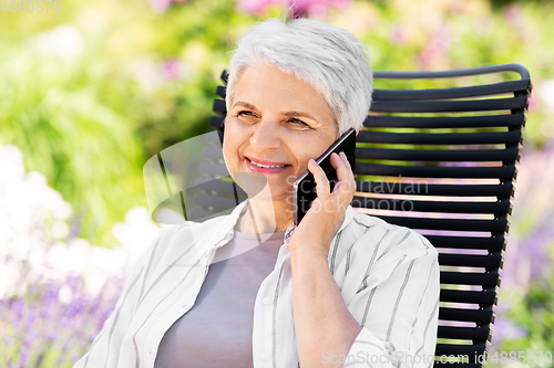 Image of happy senior woman calling on phone at garden