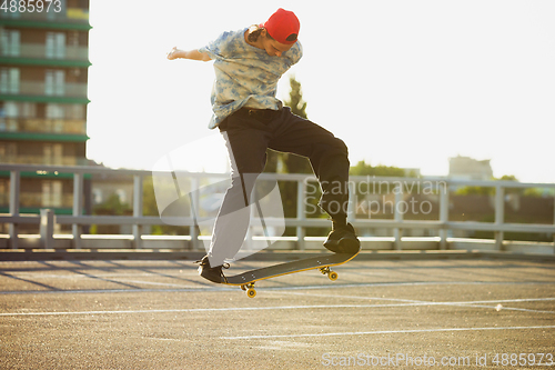 Image of Skateboarder doing a trick at the city\'s street in summer\'s sunshine