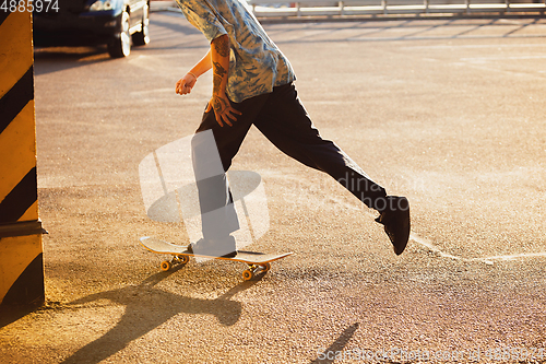 Image of Skateboarder doing a trick at the city\'s street in summer\'s sunshine