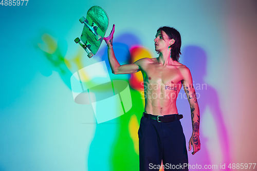 Image of Skateboarder doing a trick isolated on studio background in colorful neon light