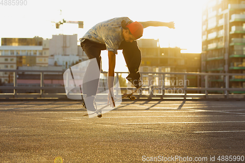 Image of Skateboarder doing a trick at the city\'s street in summer\'s sunshine