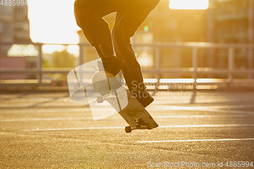 Image of Skateboarder doing a trick at the city\'s street in summer\'s sunshine