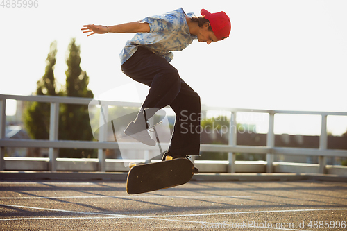 Image of Skateboarder doing a trick at the city\'s street in summer\'s sunshine