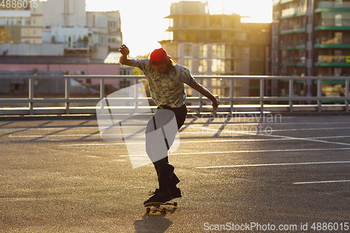 Image of Skateboarder doing a trick at the city\'s street in summer\'s sunshine