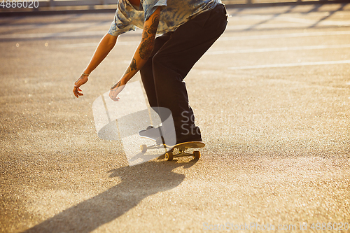 Image of Skateboarder doing a trick at the city\'s street in summer\'s sunshine