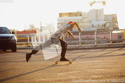 Image of Skateboarder doing a trick at the city\'s street in summer\'s sunshine