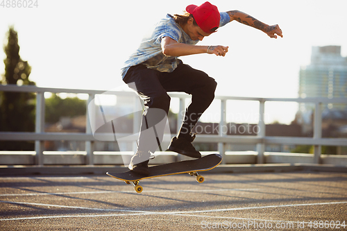 Image of Skateboarder doing a trick at the city\'s street in summer\'s sunshine