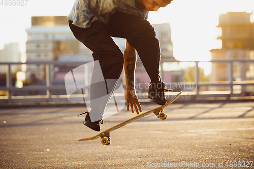 Image of Skateboarder doing a trick at the city\'s street in summer\'s sunshine