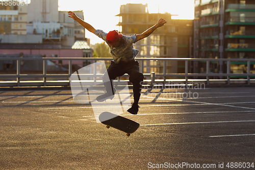 Image of Skateboarder doing a trick at the city\'s street in summer\'s sunshine