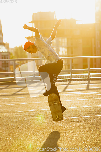 Image of Skateboarder doing a trick at the city\'s street in summer\'s sunshine