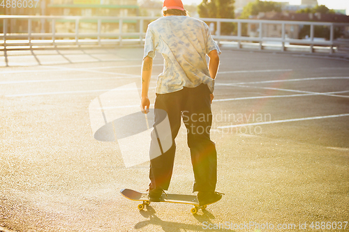 Image of Skateboarder doing a trick at the city\'s street in summer\'s sunshine