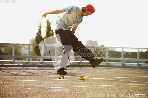 Image of Skateboarder doing a trick at the city\'s street in summer\'s sunshine