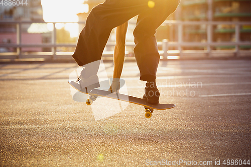 Image of Skateboarder doing a trick at the city\'s street in summer\'s sunshine