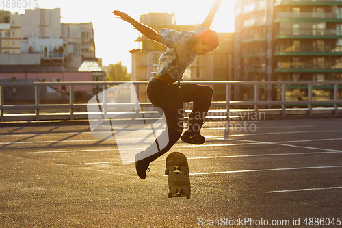 Image of Skateboarder doing a trick at the city\'s street in summer\'s sunshine