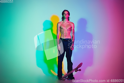 Image of Skateboarder doing a trick isolated on studio background in colorful neon light