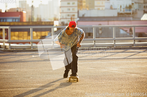 Image of Skateboarder doing a trick at the city\'s street in summer\'s sunshine