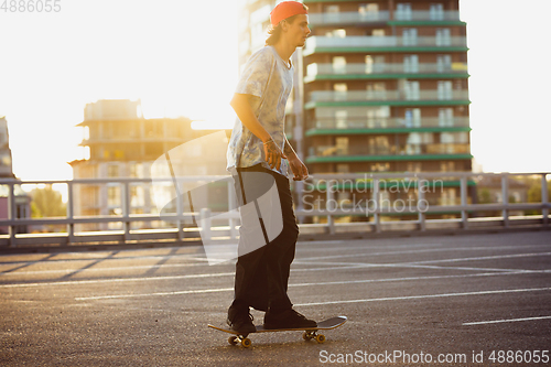 Image of Skateboarder doing a trick at the city\'s street in summer\'s sunshine