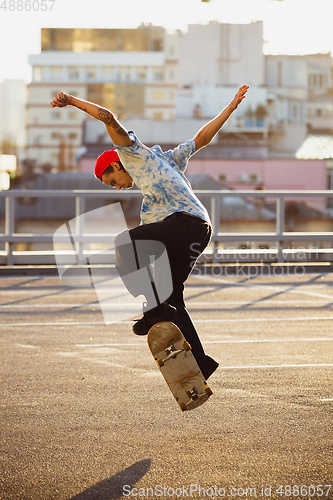 Image of Skateboarder doing a trick at the city\'s street in summer\'s sunshine