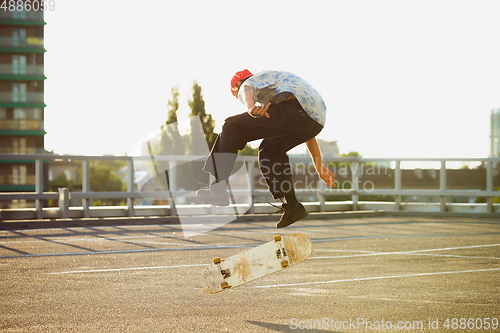 Image of Skateboarder doing a trick at the city\'s street in summer\'s sunshine